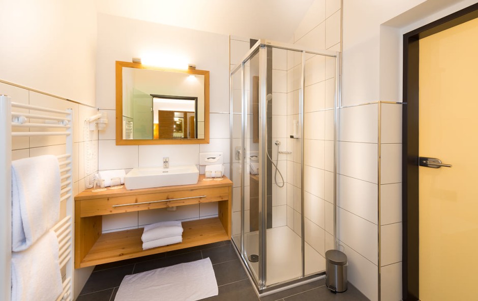 Badezimmer mit Dusche, Waschbecken und Spiegel